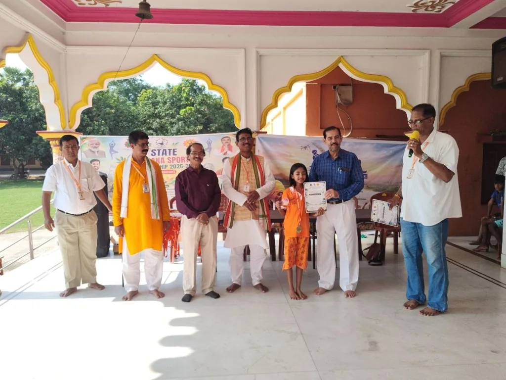 A young athlete in orange holds a certificate in the hall.