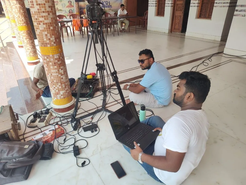 Deepayan and Nazmul sit with a camera, a sound desk and a laptop during the championship broadcast.