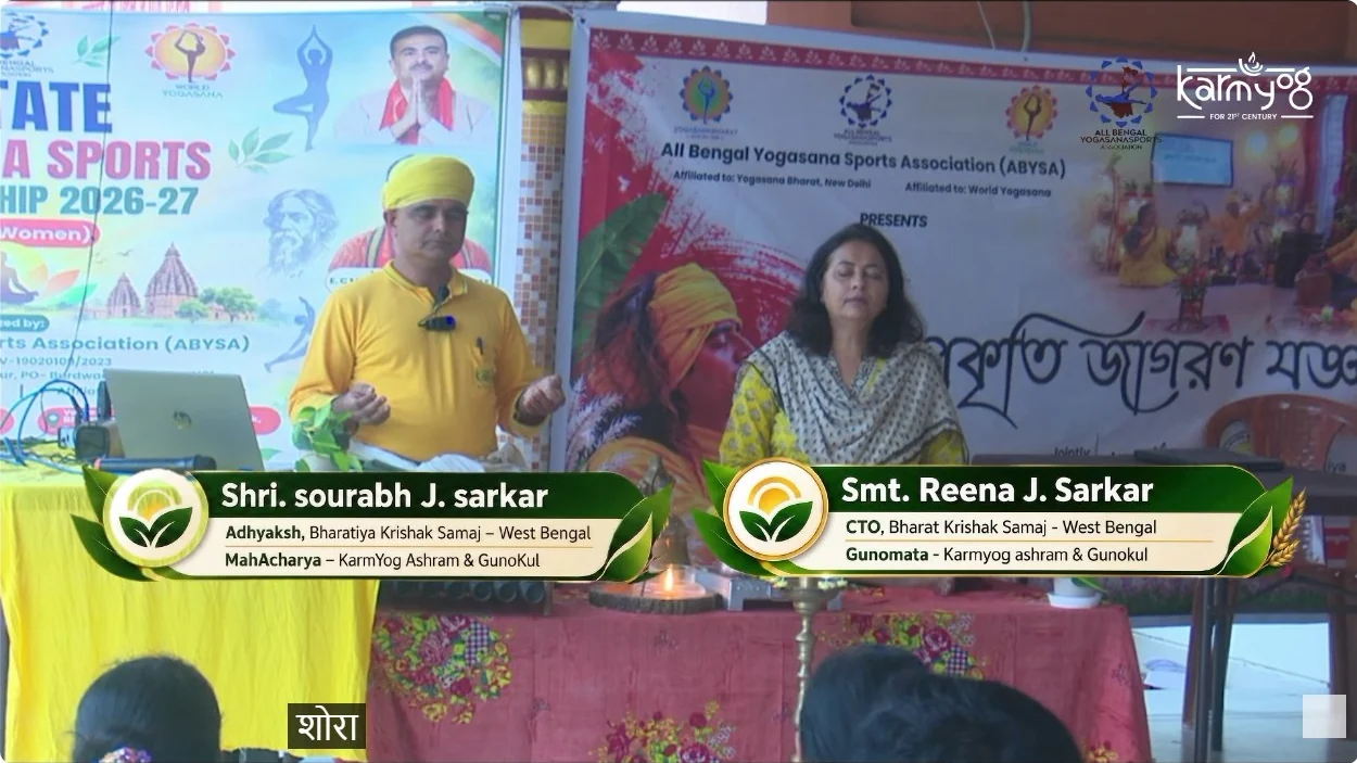 Sourabh J. Sarkar stands in yellow with a microphone while Reena J. Sarkar sits beside him. The lower thirds name him Mahacharya and her Gunomata.