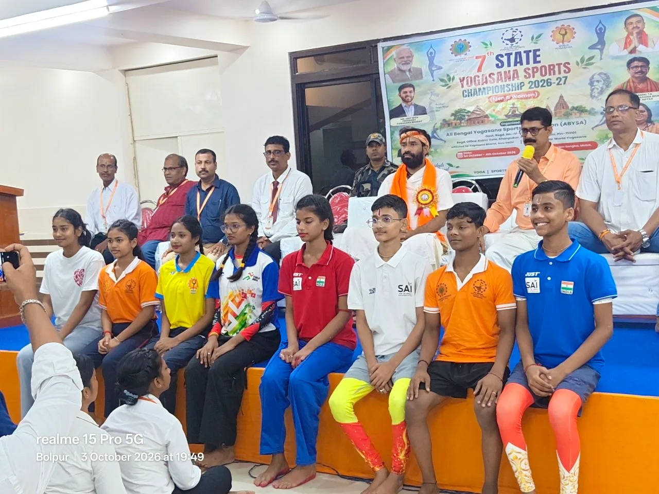 Athletes sit on the hall steps with officials of the championship standing behind them.